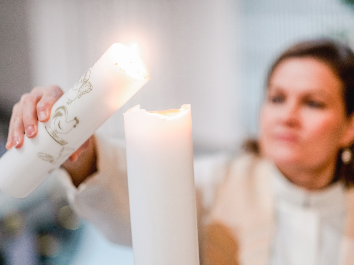 Pappi sytyttää kastekynttilän toisen kynttilän avulla.