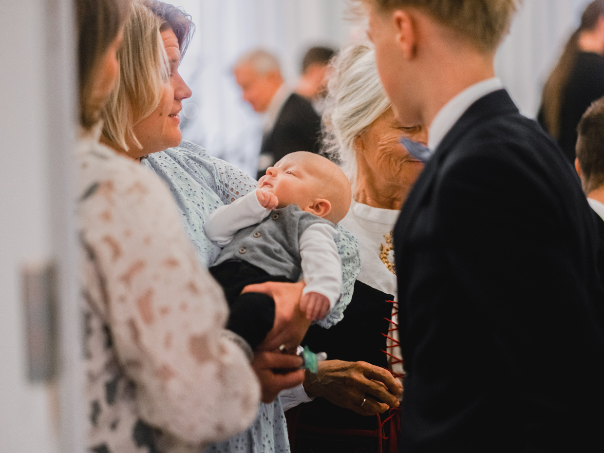 Vauva on naisen sylissä kastejuhlavieraiden ihailtavana.