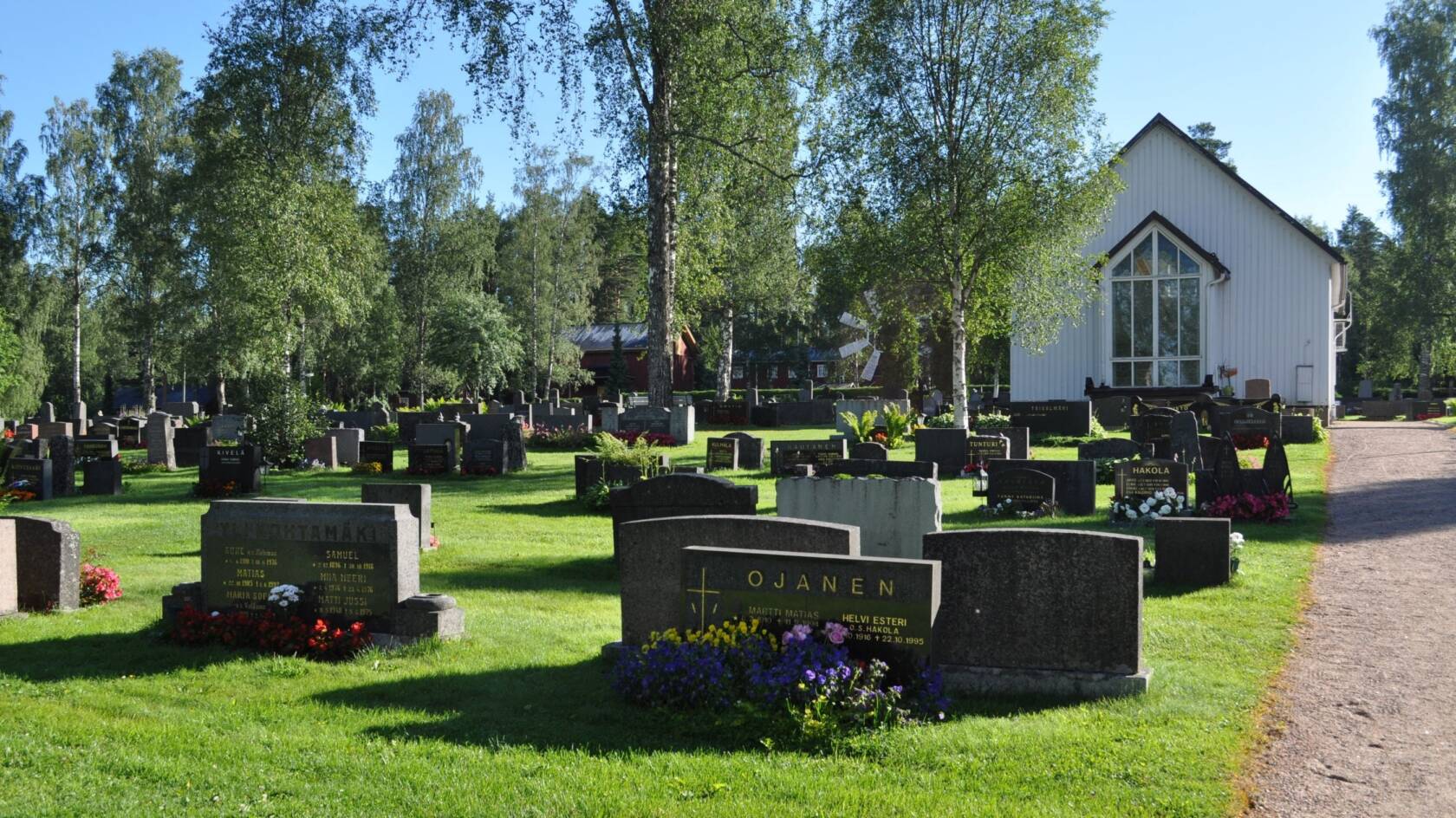 Hautakiviä Jalasjärven hautausmaalla, taustalla siunauskappeli.