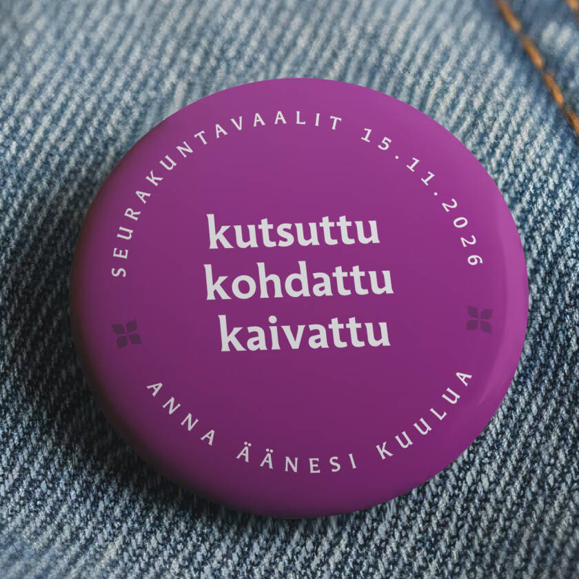 Violetti rintamerkki farkkukankaalla. Rintamerkissä teksti: ‘Seurakuntavaalit 15.11.2026 – kutsuttu, kohdattu, kaivattu – anna äänesi kuulua’