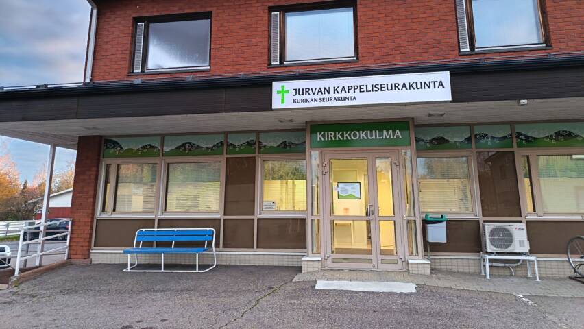 Ulkokuva Kirkkokulmasta ikkunateippausten ja valokyltin kanssa.