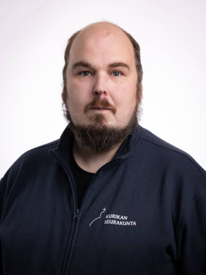 Kalju mies, jolla tumma parta ja viikset, sekä tummansininen paita.