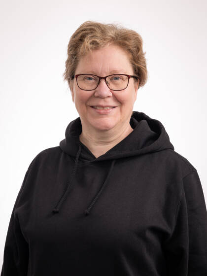 Silmälasipäinen ja vaaleahiuksinen nainen, jolla musta huppari