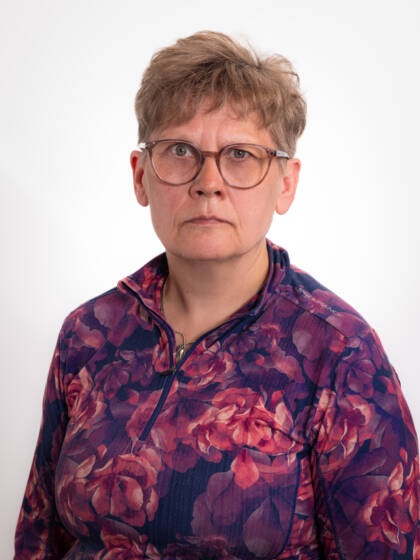 Silmälasipäinen nainen, jolla kukallinen paita